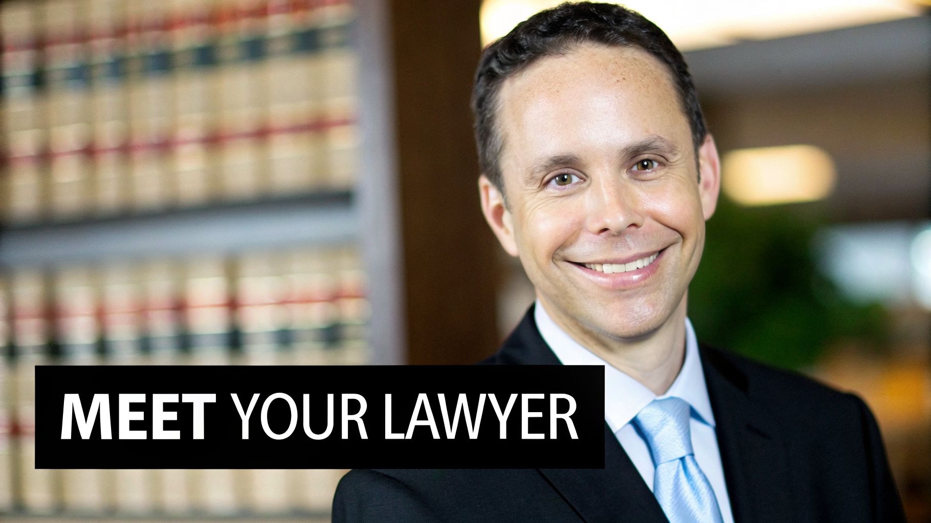 Smiling male lawyer in suit and light blue tie, standing in a law office with books, with text 'MEET YOUR LAWYER'.
