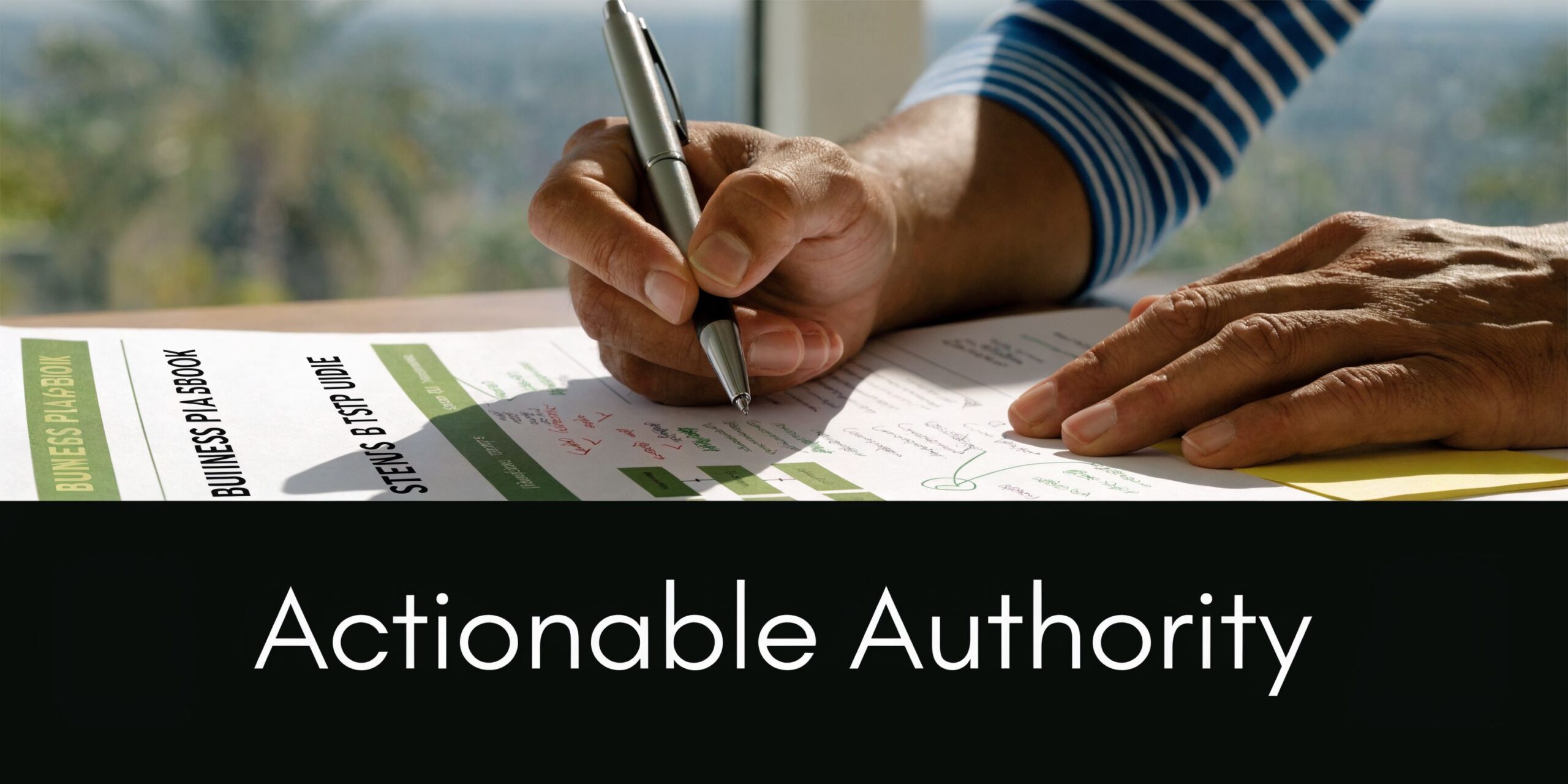 A professional writing on a business strategy document while wearing a striped long sleeve shirt.