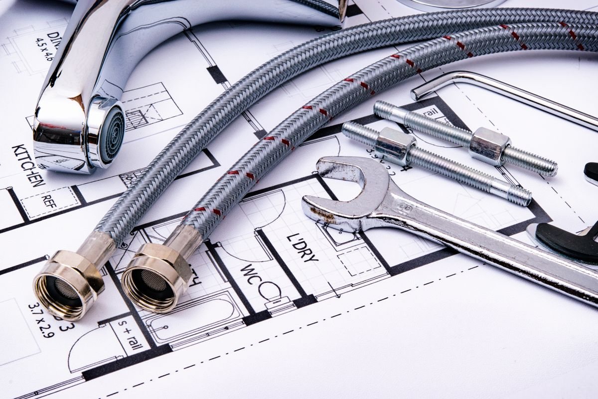 Plumbing tools, hoses and a tap laid out on a floor plan